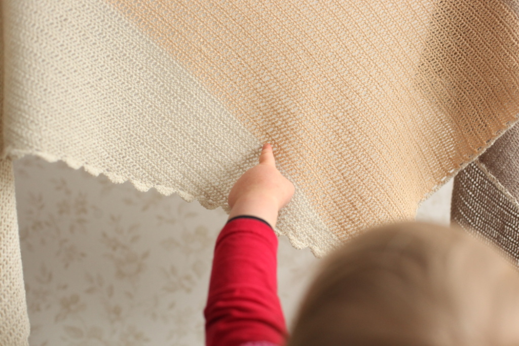 A toddler pointing at the crocheted shawl