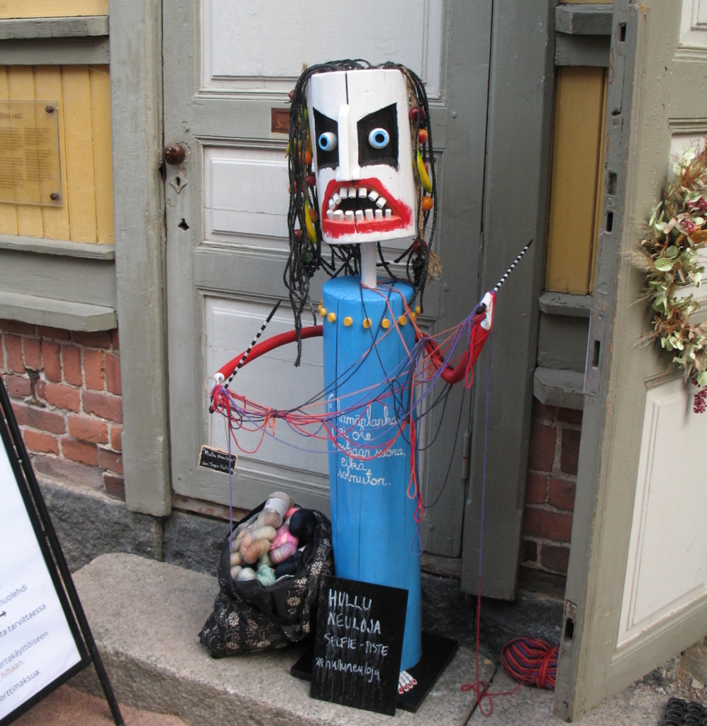 A wooden statue of a crazy knitter